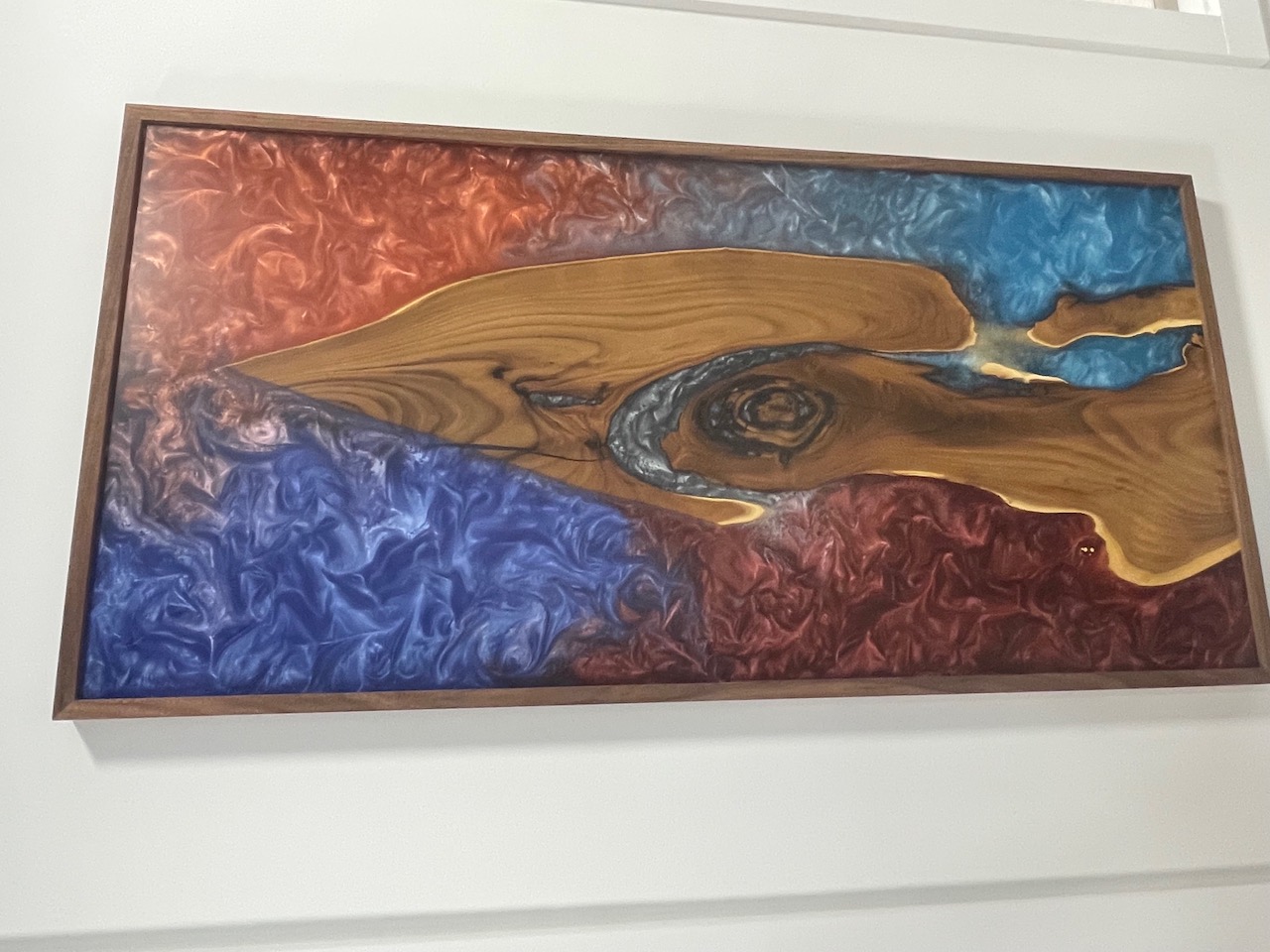 Framed live-edge epoxy wall art with copper-red and deep blue marbled resin around a walnut-toned slab, by Lost Species